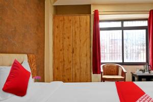 Schlafzimmer mit einem Bett mit roten Kissen und einem Fenster in der Unterkunft OYO Flagship Bliss Inn in Lukerganj