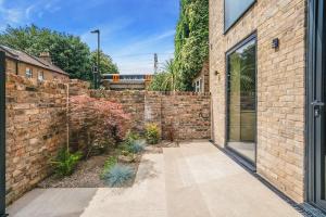 a brick wall with a courtyard in front of a building at Tottenham- Exquisite 4-Bed Retreat with Ping Pong and Pool - Sleeps 7, Free Parking, Contractors & Long Stays Welcome in London