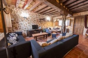 a living room with a blue couch and a stone wall at La Hacendera Entre Hoces - 20-28pax-10 hab con baños en suite in Maderuelo