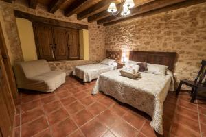 1 dormitorio con 2 camas y 1 silla en una habitación en La Hacendera Entre Hoces - 20-28pax-10 hab con baños en suite en Maderuelo