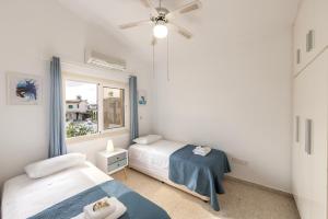 a bedroom with two beds and a window at Ayia Thekla Sea Breeze Villa in Ayia Napa