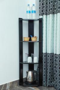 a black shelf with a tea kettle and water bottles at Airport Colombo Pocket Paradise in Seeduwa