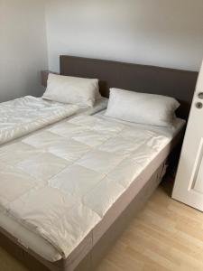 a large bed with white sheets and pillows on it at Moderne Ferienwohnung an der Ostsee im Haus Leuchtfeuer in Diedrichshagen