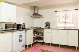a kitchen with white cabinets and a microwave at 9Arches in Vila Nova de Poiares