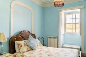a bedroom with a bed with blue walls and a window at 9Arches in Vila Nova de Poiares