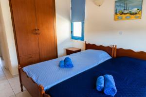 um quarto com 2 chinelos azuis numa cama em Arsinoe Beach Village Block 9 em Pólis