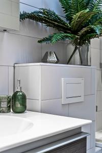 a bathroom with a white counter and a plant at Kensington Oasis Central London 2BR Private House - Near Harrods, Kensington Palace, and other London Attractions in London