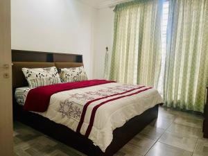 a bedroom with a bed with a red and white blanket at Luxe Isle by Harolty, East Legon in Accra