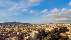 a view of a city with buildings and mountains at Touch the sky BCN in Hospitalet de Llobregat