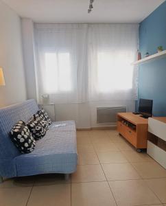 a living room with a blue couch and two windows at Apartamento Gerimar - Gelida/Bcn in Gélida