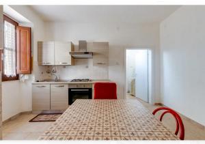 a kitchen with a table and two red chairs at Casa vacanze Oristano Ghilarza Sardegna in Ghilarza