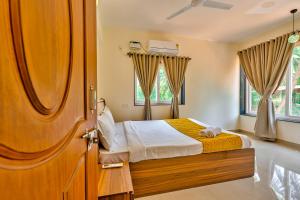 a bedroom with a bed and a wooden door at Golden Sun Ray's Villas in Baga