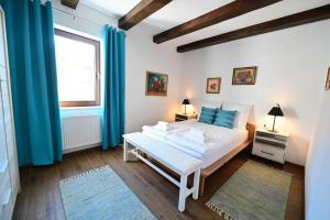 1 dormitorio con cama blanca y cortinas azules en FLH - Casa Doris, en Sibiu