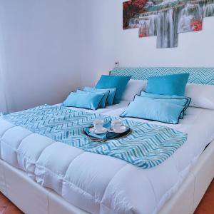 - un lit blanc avec des oreillers bleus et un plateau dans l'établissement Camera Panoramica in Villa vista Mare e Vesuvio, à Massa Lubrense