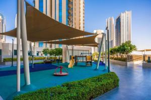 a playground with a slide and a swing at 2bdr - Pool - Emaar - Creek Harbour in Dubai