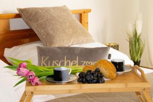 ein Tablett mit Essen auf einem Bett mit Kaffeetassen und Obst in der Unterkunft Ferienwohnung in Schönwald Schwarzwald in Schönwald