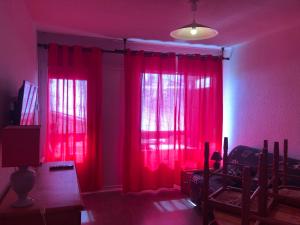 a living room with red curtains and a tv at plein sud in Saint-Aventin