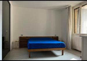 1 dormitorio con 1 cama azul en una habitación blanca en La casa di Wayne, en Cologno Monzese