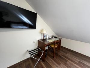 Habitación con escritorio y TV en la pared. en Memel Hotel en Klaipėda