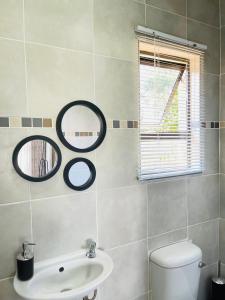 a bathroom with a sink and two mirrors on the wall at SeaBreeze Relaxa BnB in Hibberdene
