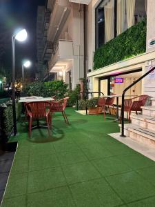 un patio con mesa, sillas y césped verde en Hotel Sylva, en Cattolica