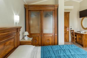 ein Schlafzimmer mit einem Bett und einem Holzschrank in der Unterkunft Hotel Sa Suergia in Villasimius