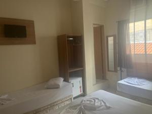 a room with two beds and a tv and a window at H POUSADA DO BENTO in Aparecida
