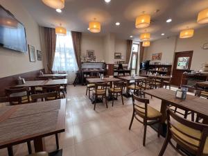 a restaurant with wooden tables and chairs and a piano at Memel Hotel in Klaipėda