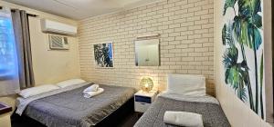 ein Schlafzimmer mit zwei Betten und einem Spiegel in der Unterkunft Casa Cinco Kalbarri - Kalbarri, WA in Kalbarri