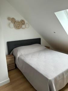 um quarto com uma cama branca e dois relógios na parede em Charmant Appt Duplex - 8 Personnes em Saint-Nectaire