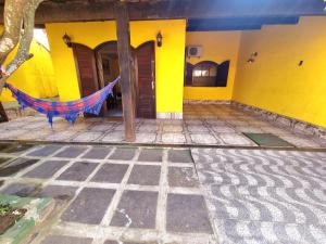a yellow house with a hammock in front of it at Casa Praia Grande - Arraial do Cabo in Arraial do Cabo