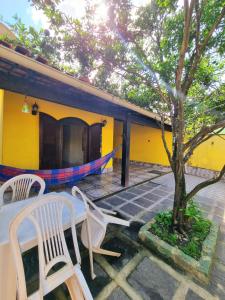 阿拉亞爾多卡博的住宿－Casa Praia Grande - Arraial do Cabo，两把椅子和一棵树在房子前面
