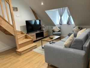 uma sala de estar com um sofá e uma televisão em Charmant Appt Duplex - 8 Personnes em Saint-Nectaire