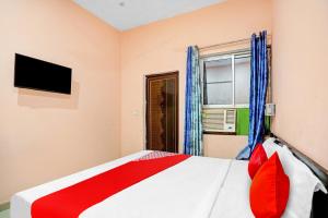 Un dormitorio con una cama con almohadas rojas y una ventana en Flagship Hotel Status en Bareilly