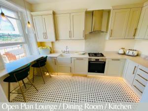 eine Küche mit weißen Schränken, einer Spüle und einem Tisch in der Unterkunft The Paragon Penthouse - Stunning Views over Bath! in Bath