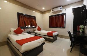 a bedroom with two beds and a desk and a piano at Hotel Suraj Inn in Surat