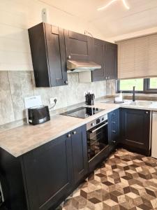 a kitchen with black cabinets and a sink at Magpie 6 HuntersMoon-Warminster-longleat-Bath in Warminster