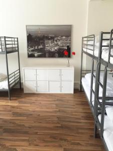 a bedroom with two bunk beds and a dresser with a painting at MAC City Hostel in Hamburg