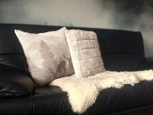 a black leather couch with a pillow and a blanket at Schöne Zeiten Ferienwohnung in Baiersbronn