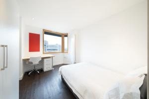 a bedroom with a bed and a desk and a window at Cosy Studios and Apartments at Chapter Aldgate in London in London