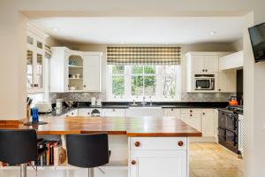 una cucina con armadi bianchi e ripiano in legno di Garth Lodge with Tennis Court and Pool a Wimborne Minster
