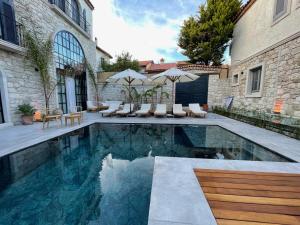 a swimming pool in a backyard with chairs and umbrellas at Rhea Alaçatı Boutique Hotel in Alacati