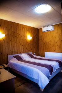 een slaapkamer met een groot bed en houten wanden bij PENSIUNEA ETAP in Arad