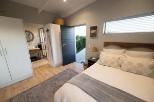 a bedroom with a large bed and a bathroom at Chapmans Corner Studio in Noordhoek