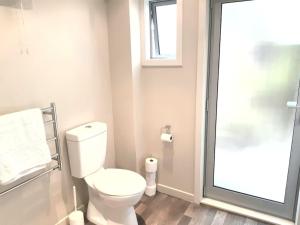 Un baño con inodoro blanco y ventana. en Vauxhall Private Suite, en Dunedin 4 fotos más