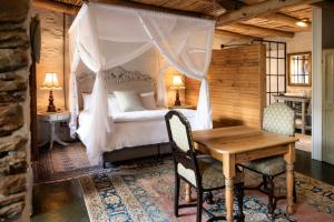 a bedroom with a bed and a wooden table and chairs at Olive Stone Farm Cottages in Montagu