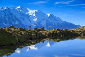 a man standing on the edge of a lake in front of a mountain at Studio de Balme - Happy Rentals in Chamonix-Mont-Blanc