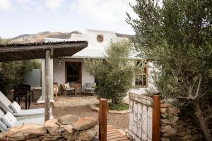 a white house with a porch and a fence at Olive Stone Farm Cottages in Montagu