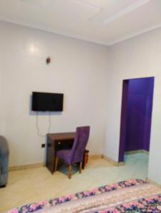 a room with a desk and a tv and a purple chair at MUSAROQ HOTEL in Lagos