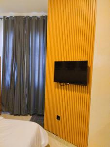 1 dormitorio con una pared amarilla y TV. en MUSAROQ HOTEL, en Lagos
